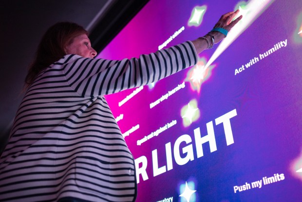 Attendees tap a spark reflecting what they learned after watching "Holocaust 101," an interactive video shown inside the Spark Interactive bus during its launch event at Crownair Aviation in San Diego on May 3, 2026. (McKenzie Patterson / For The San Diego Union-Tribune)