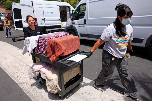 San Diego Humane Society staff members Natalia Garcia, left, and Marielle Legaspi wheel rescued cats into the facility on Monday. (K.C. Alfred / The San Diego Union-Tribune)