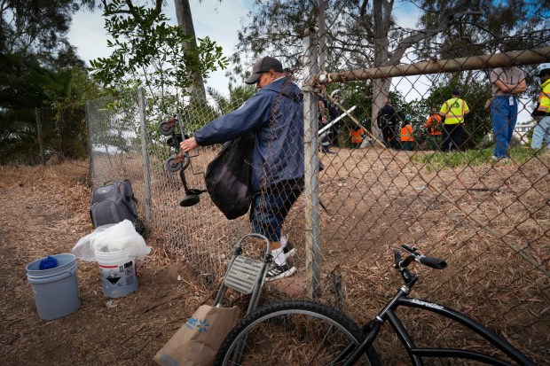 Jason Borja removes what he can from his encampment near the state Route 94 westbound freeway during a recent abatement of encampments. (Nelvin C. Cepeda / The San Diego Union-Tribune)
