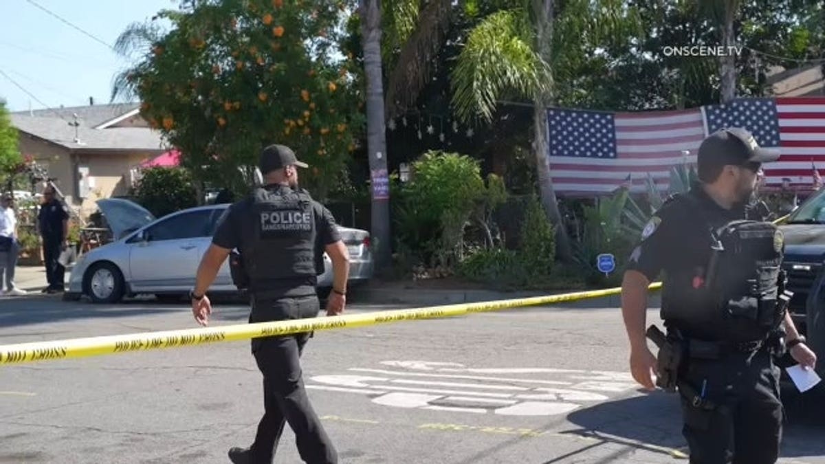 Police officers posted near yellow tape, with American flags in the background