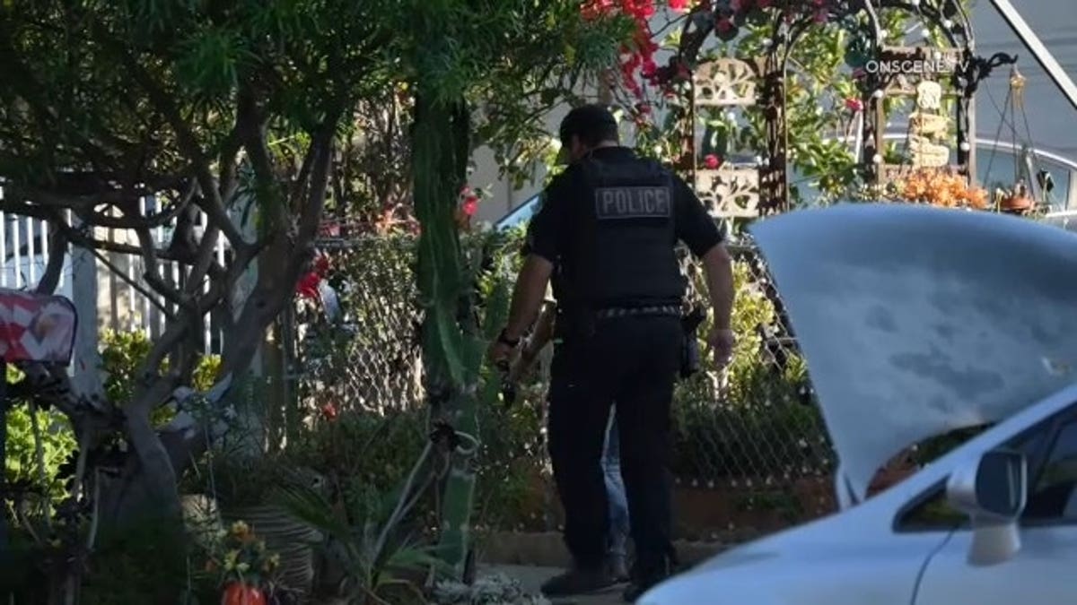 An Escondido police officer moves down the front walkway outside the home