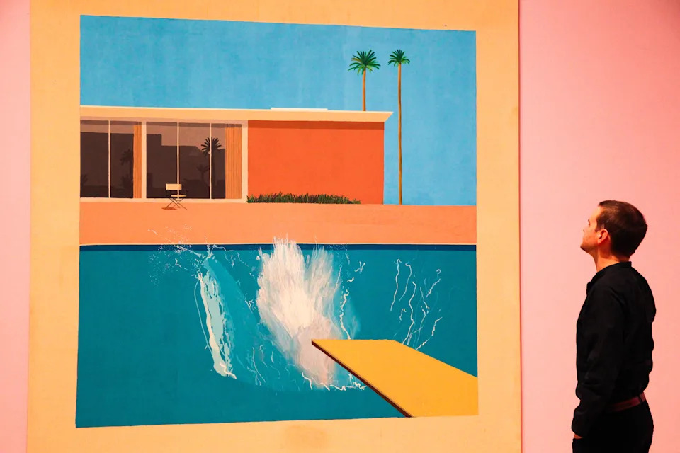 A member of gallery staff looks at Hockney's painting titled "A Bigger Splash."