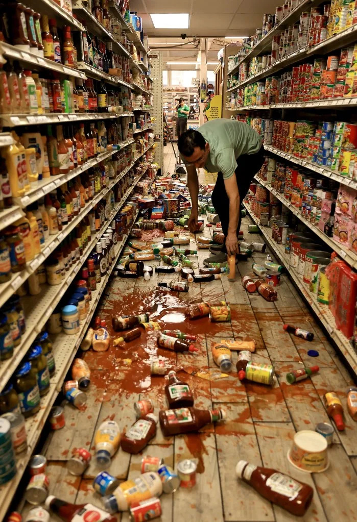 Redwood Valley Market owner Alex Chehada picks up items that fell off the shelves. Kent Porter/The Press Democrat via AP