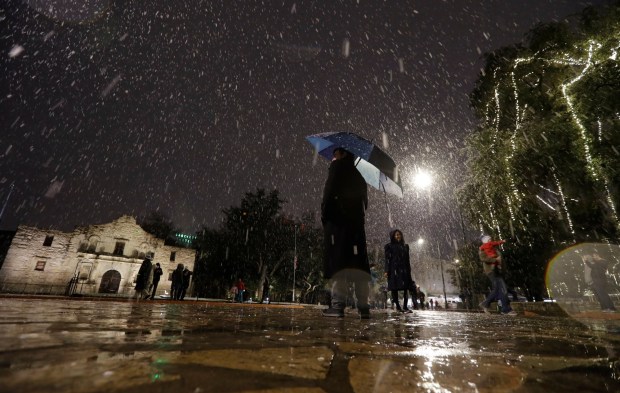 Visitors walk near the Alamo as snow falls in downtown San Antonio, Thursday, Dec. 7, 2017. (AP Photo/Eric Gay)