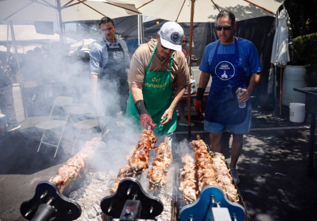Harris Charitiou, center, prepares Souvla as Nick Antoniou, right, keeps watch at the Meze & Cheese Bar at the San Jose Greek Festival at St. Nicholas Greek Orthodox Church in San Jose, Calif., on Sunday, May 31, 2026. (Nhat V. Meyer/Bay Area News Group)