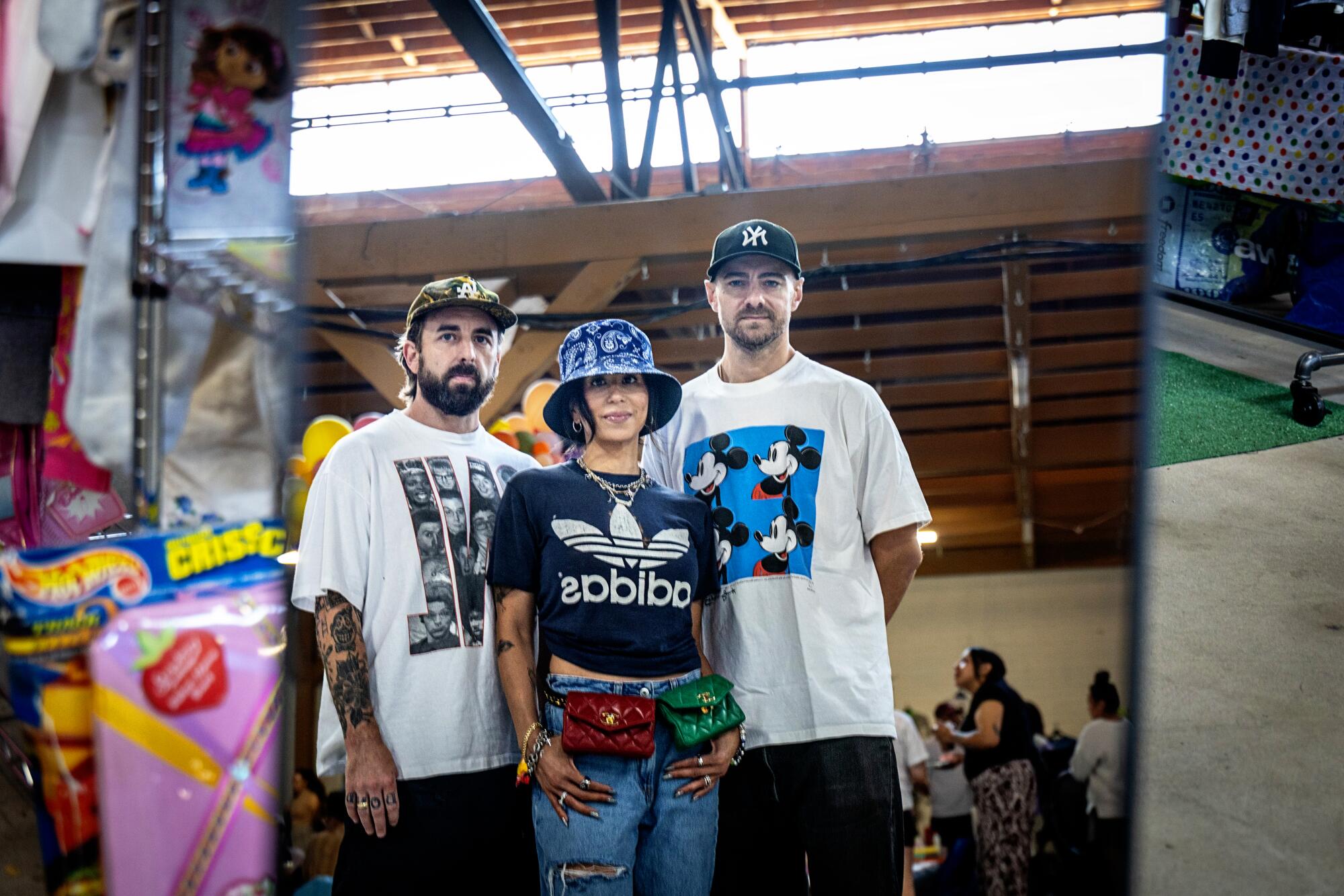 Three people in graphic T-shirts and hats.