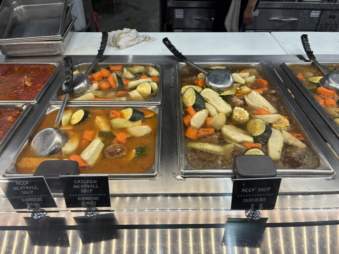 An array of metal serving dishes holds stews of meat and vegetables.