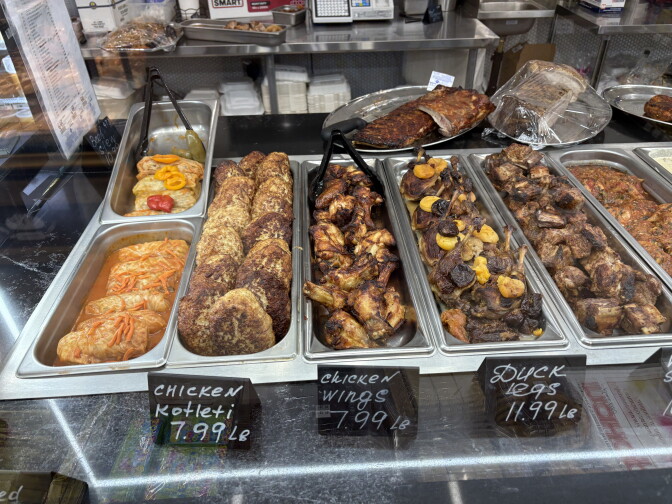 A selection of metal serving dishes has different Russian foods, side by side. One says Chicken Kotleti, another says Chicken wings and another says Duck Legs.