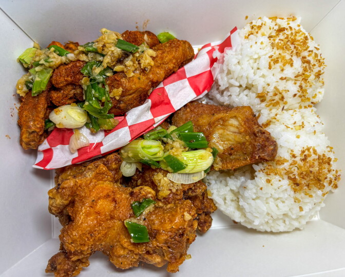 An overhead view of the House Box Specialty at Mama Hieu's, featuring crispy Vietnamese fried chicken wings coated in garlic butter sauce with green onion, alongside two scoops of white rice topped with fried garlic.