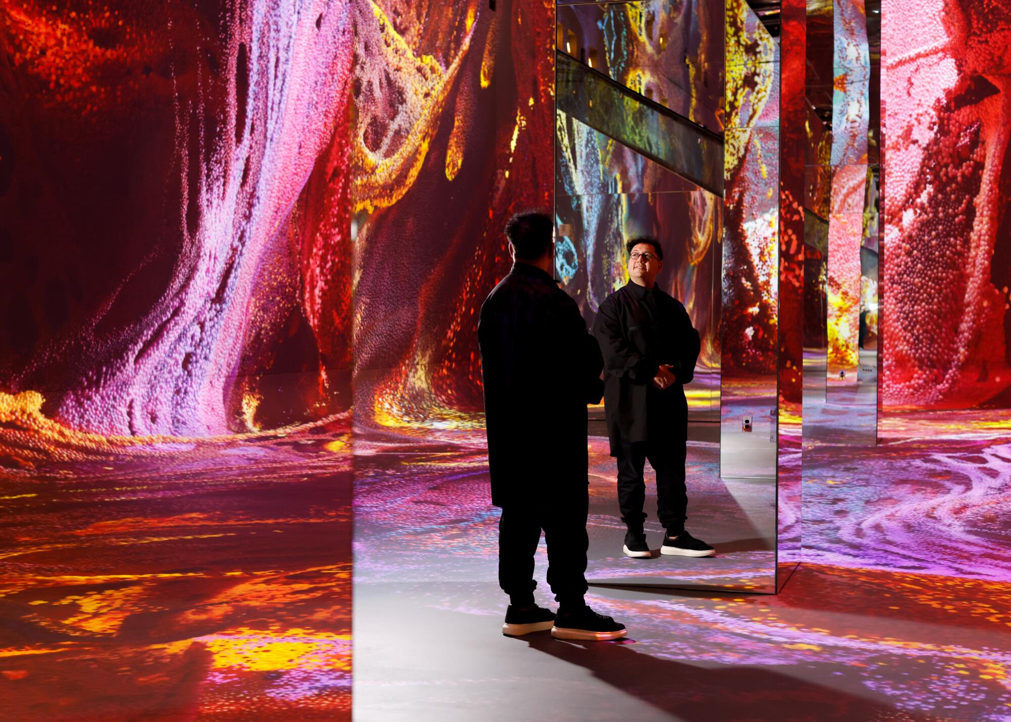 A man stands inside an immersive AI arts museum.