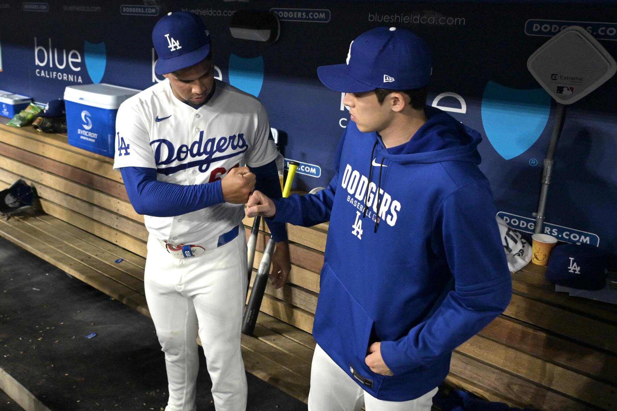 Edgardo Henriquez, left, bumps fists with Roki Sasaki in the dugout at Dodger Stadium on May 14.