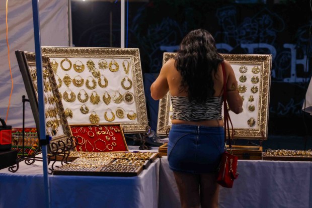 A festivalgoer looks at jewelry in a vendor's booth during the Oakland First Fridays event along Telegraph Avenue in Oakland, Calif., Friday, April 3, 2026. (Ray Chavez/Bay Area News Group)