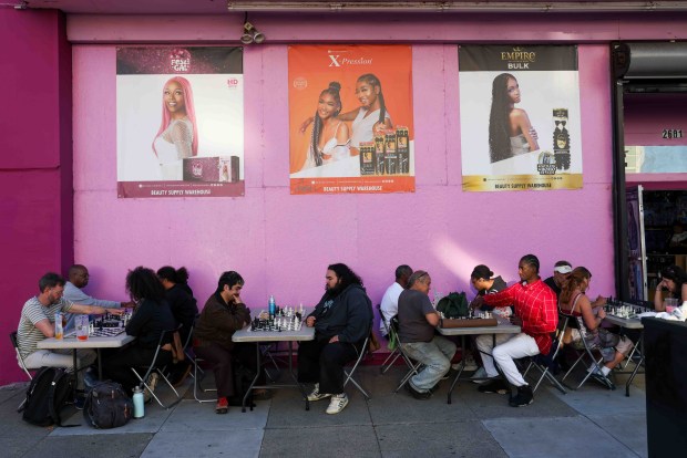 Festivalgoers play chess outside a beauty shop during the Oakland First Fridays event along Telegraph Avenue in Oakland, Calif., Friday, April 3, 2026. (Ray Chavez/Bay Area News Group)