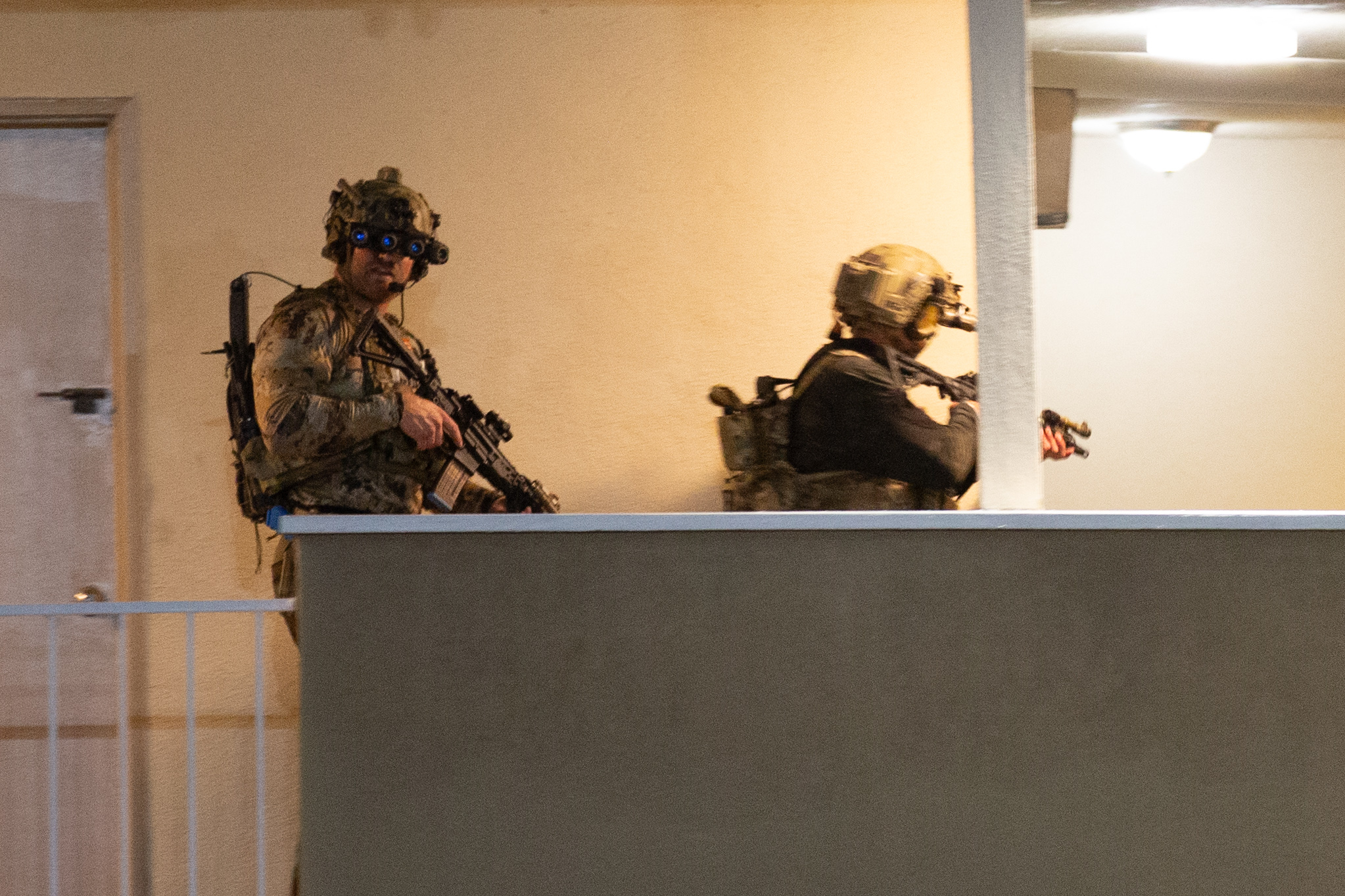 One soldier looks over the railing while another aims a...