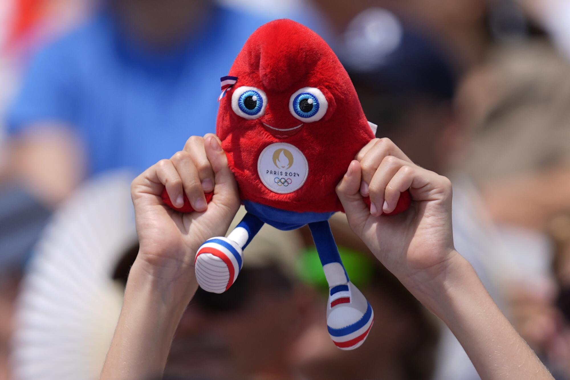 A spectator holds a Phryge, the Olympic mascot.