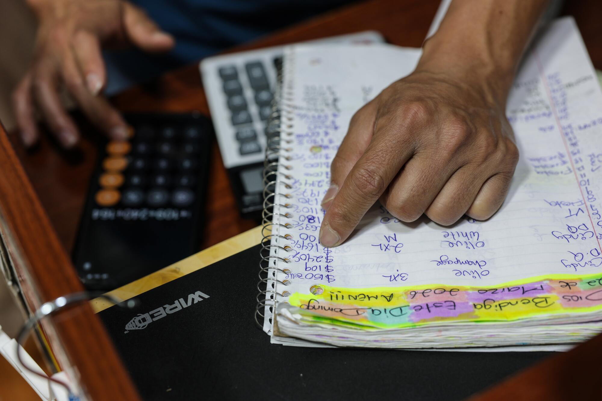 Joel Galvez reviews sales numbers in a spiral notebook in his store