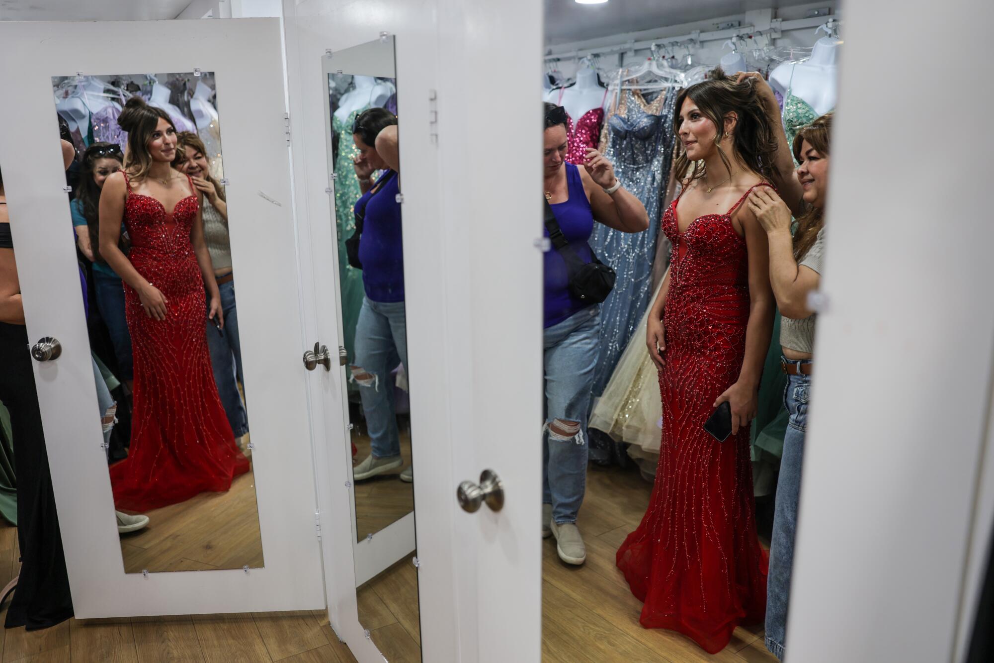 A young woman is fitted for a red prom dress