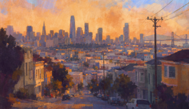 A colorful cityscape at sunset shows a downhill street lined with houses, cars, utility poles, and a distant skyline with tall buildings and a bridge.