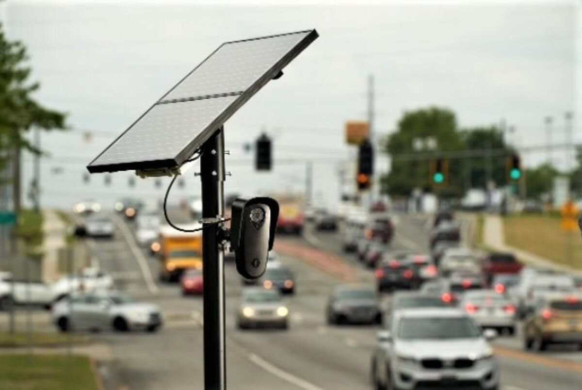 A device consisting of a flat panel on a pole and a camera