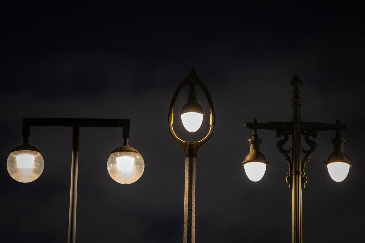 Three different styles of streetlamps: Two have double bulbs and one features a single bulb