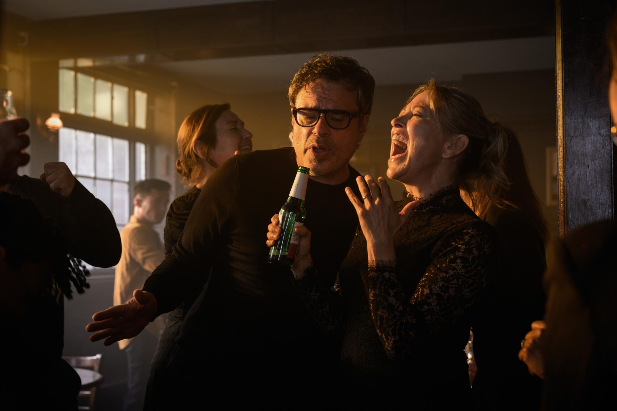 A man and a woman singing into a beer bottle.