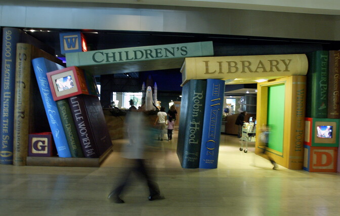 Giant book displays lay at the entrance of a library section. The books on top read "Children's Library."