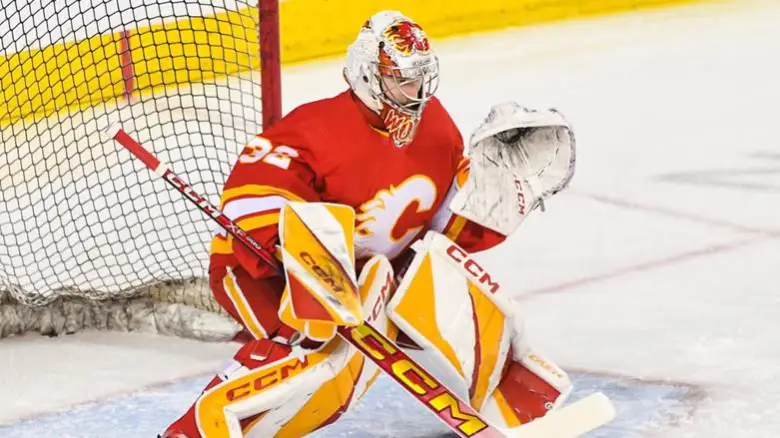 Calgary Flames goaltender Dustin Wolf squaring up to a shot on home ice.
