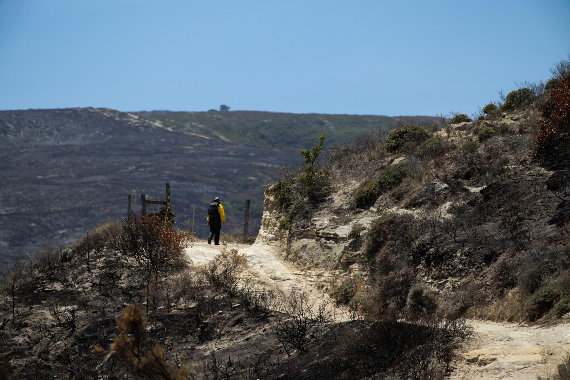 A person hikes along a scorched mountain.