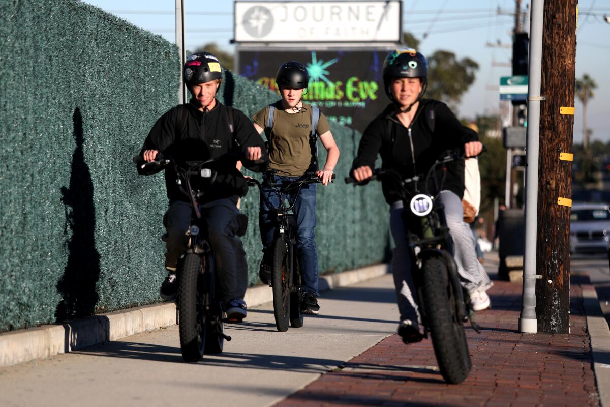 E-bikers ride along the 1400 block of Artesia Boulevard near Mira Costa High School in Manhattan Beach.
