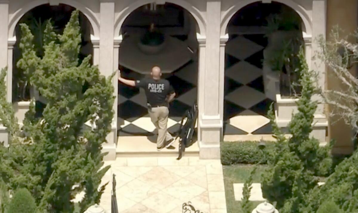 An officer stands outside an entry to the Newport Coast home of Jamshid Ghomi, while a search of the property was underway.