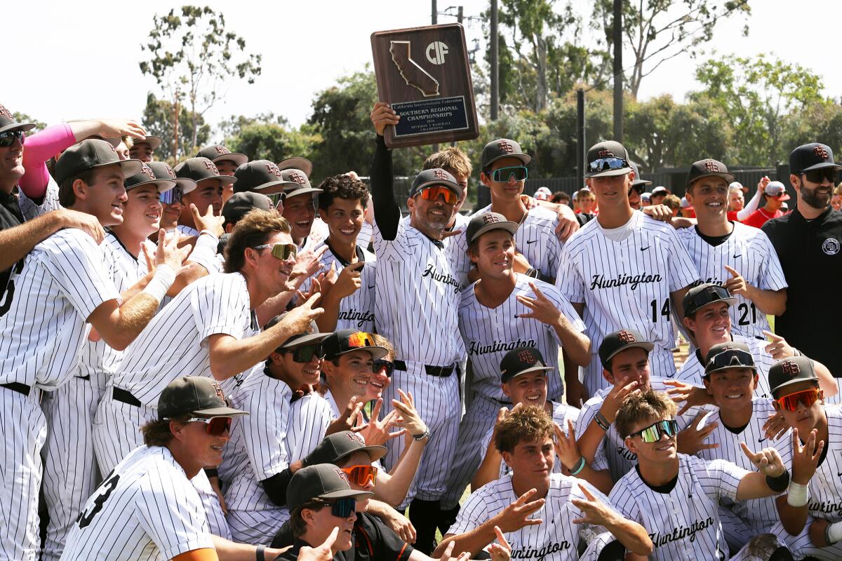 Huntington Beach coach Benji Medure holds up the trophy after the CIF State Southern California Regional Division I final.