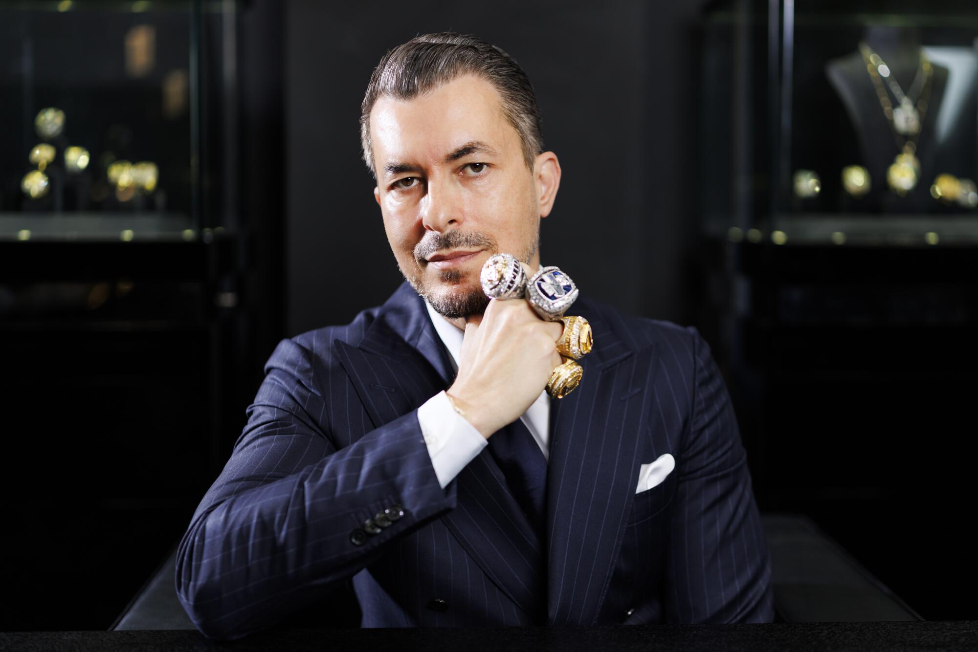 Jason Arasheben poses with some of the sports championship rings he has crafted over the years.