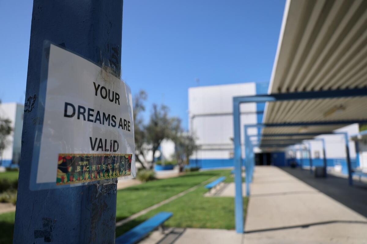  A white sign taped to a pole on a school campus reads, Your dreams are valid