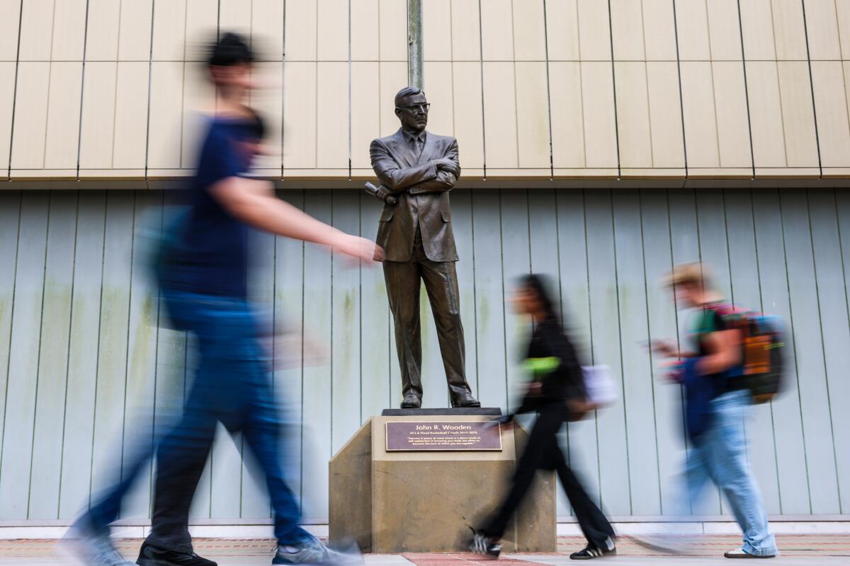 Students walk past the John Wooden statue outside Pauley Pavilion on the UCLA campus.