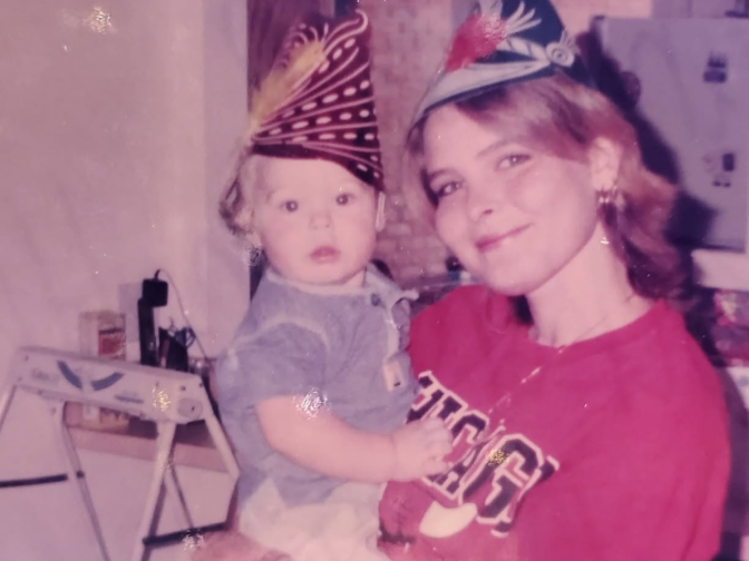 An old photograph of a woman in a read sweat shirt holding a baby.