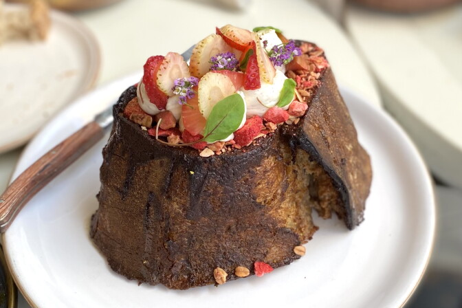 A brown pastry crust surrounds an interior made up of sliced strawberries, other fruit and leaves.