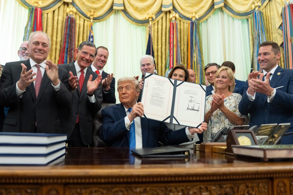 President Trump displays the signed "Secure America Act" during a ceremony in the Oval Office.