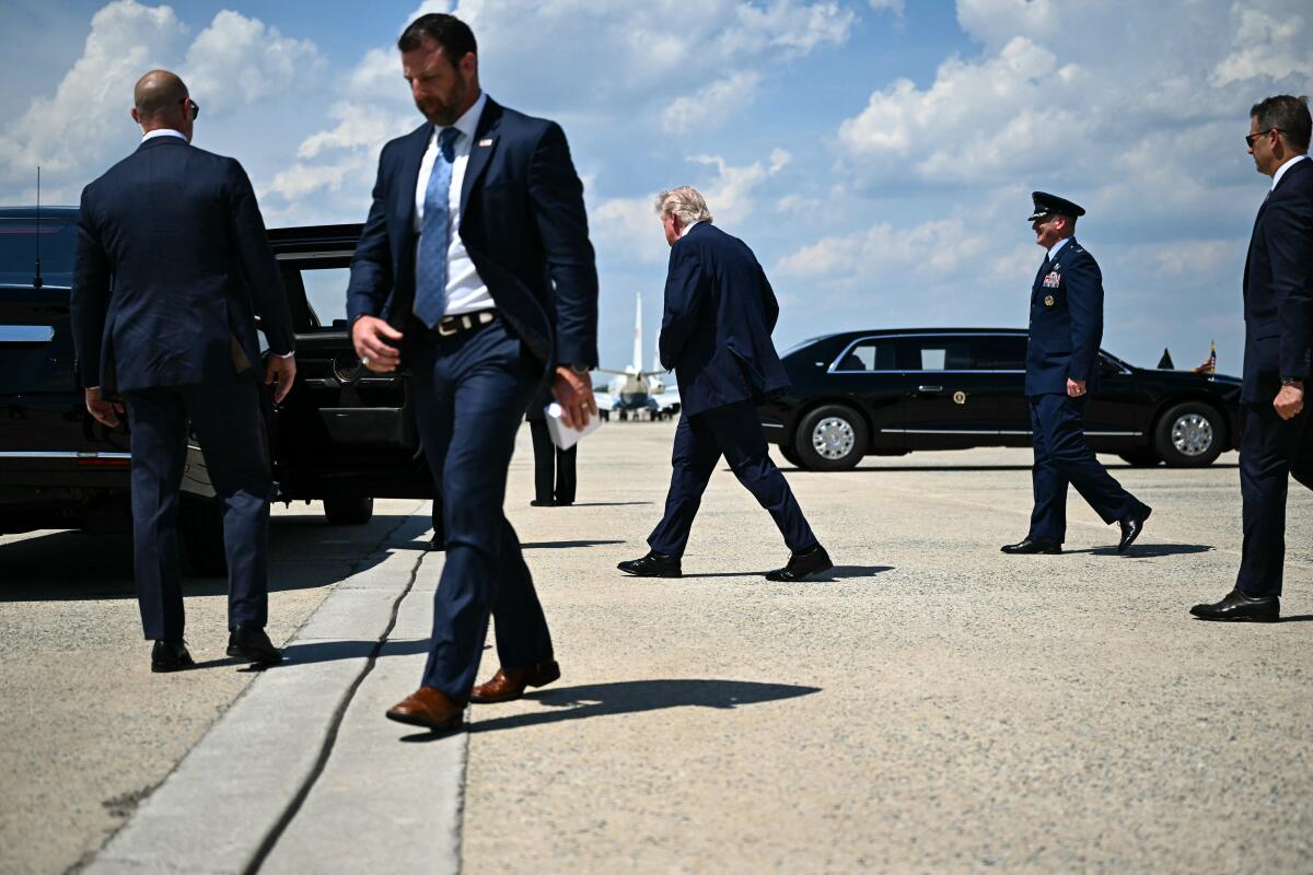 Secretary of Homeland Security Markwayne Mullin, left, and President Donald Trump, center, walk to the motorcade