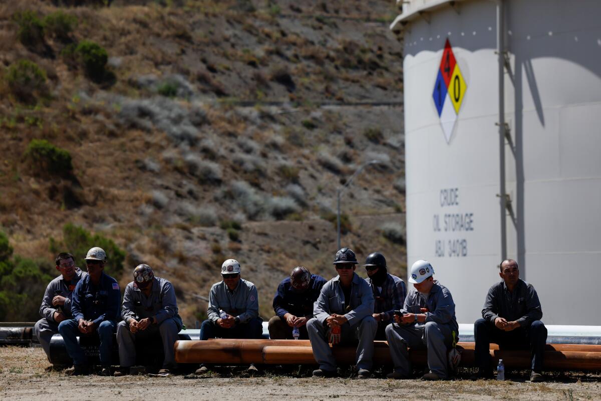 Workers in front of a crude oil storage container
