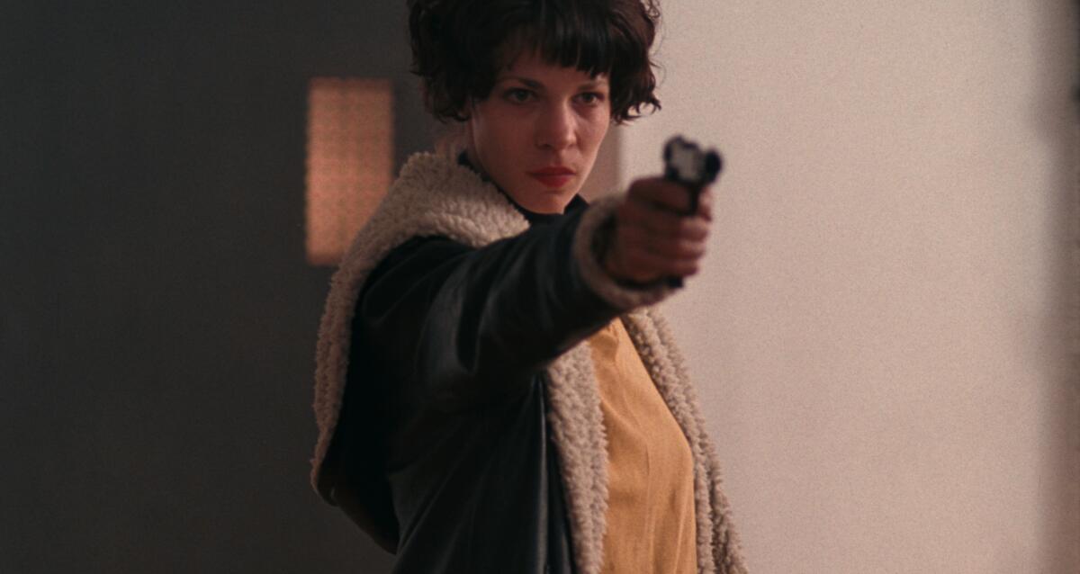 A woman points a pistol.