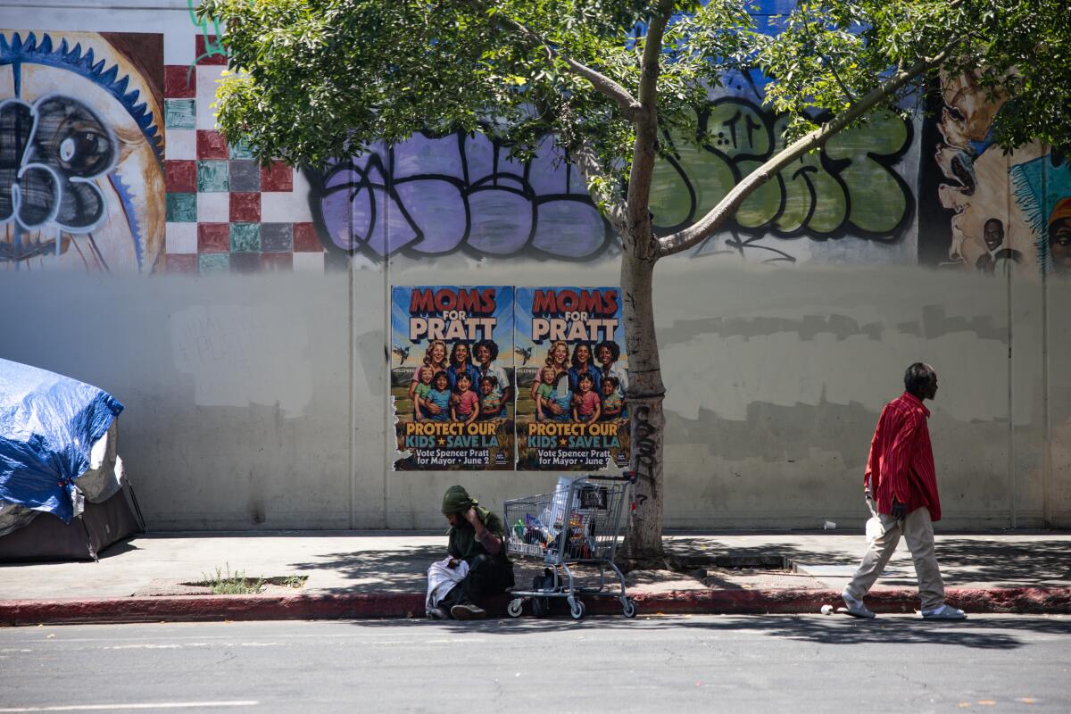People walk past Spencer Pratt's mayoral campaign posters