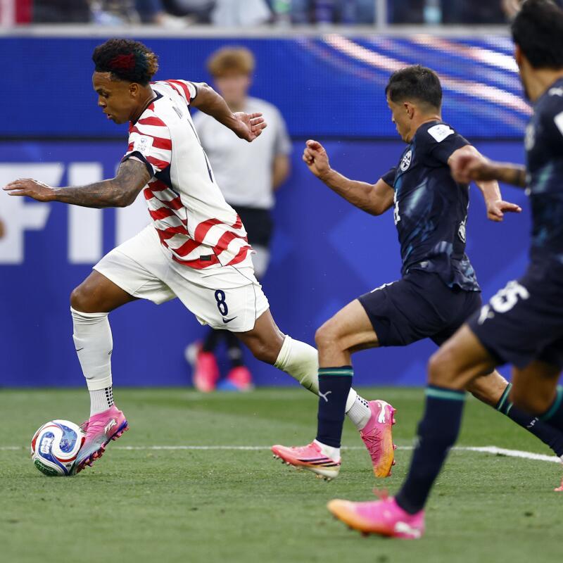 Weston McKennie sprints with the ball in front of two Paraguay defenders.