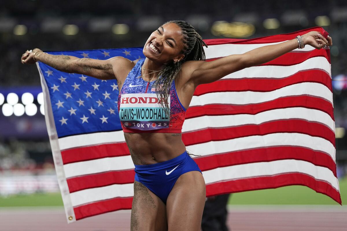 Tara Davis-Woodhall carries the U.S. flag after winning the women's long jump at the 2025 world championships in Tokyo.