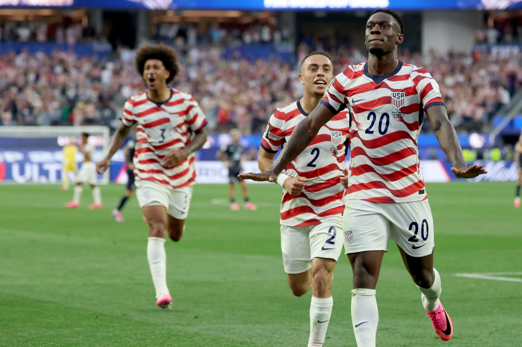 U.S. forward Folarin Balogun celebrates with Sergino Dest and Chris Richards after scoring during a World Cup win.