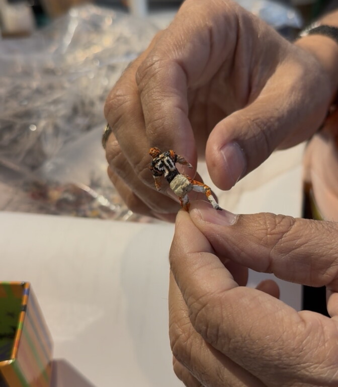 A tiny miniature made from chewing gum wrappers depicts a football player with a orange and black jersey