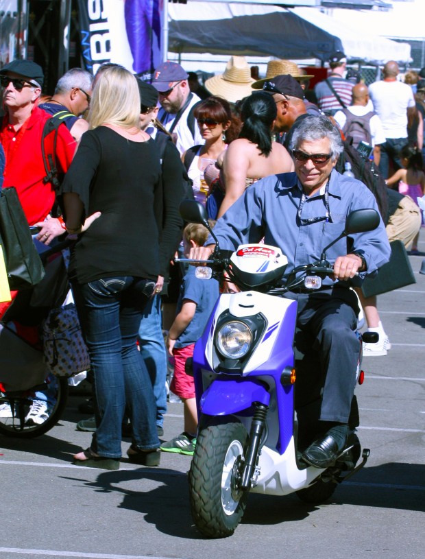 Jim Michaelian riding on his scooter around the circuit of the Acura Grand Prix of Long Beach. (Photo by Chris Esslinger)