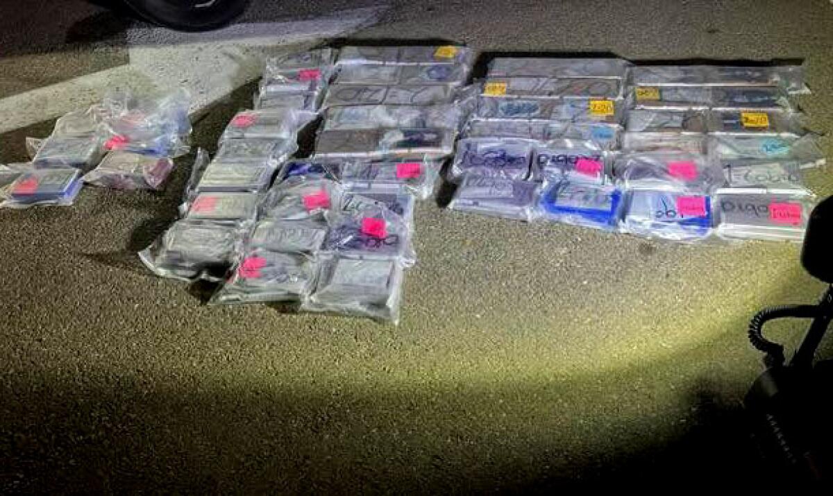 Several plastic packages of cocaine and fentanyl laid out on the pavement