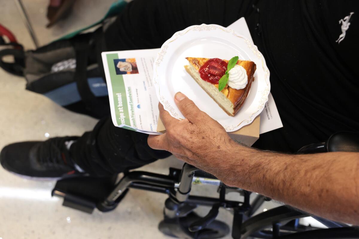 A man holds a slice of cake on a plate.