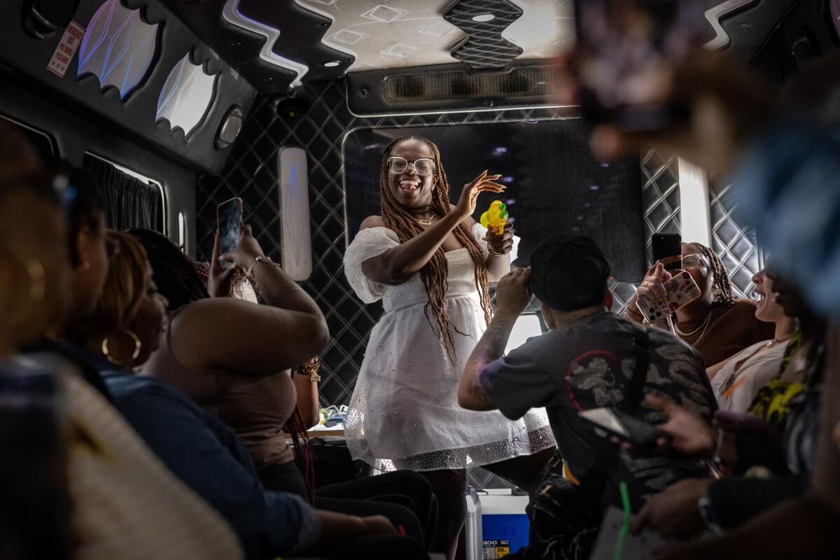 Daisy Miles, owner of the Daisy BLK LA Food Tour spays shots on the party bus.