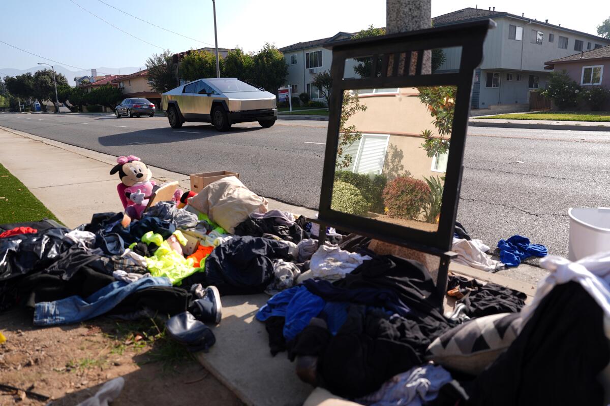 Clothes and a mirror crowd the sidewalk.